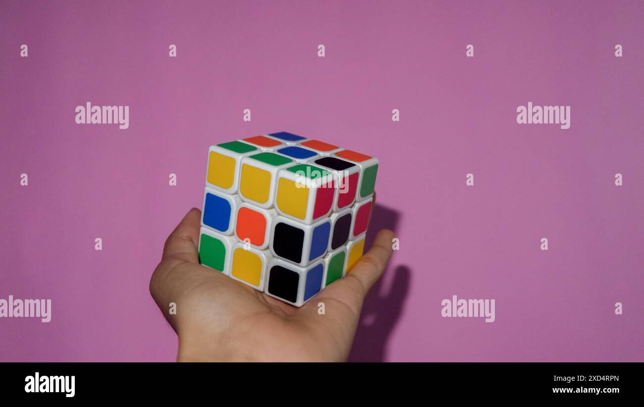 Foto von jemandes Hand, die Rubik mit rosa Hintergrund hält, Wonosobo, Indonesien Stockfoto