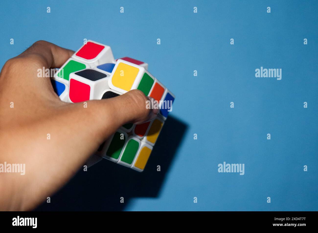 Foto einer Person, die einen rubik auf hellblauem Hintergrund hält Stockfoto