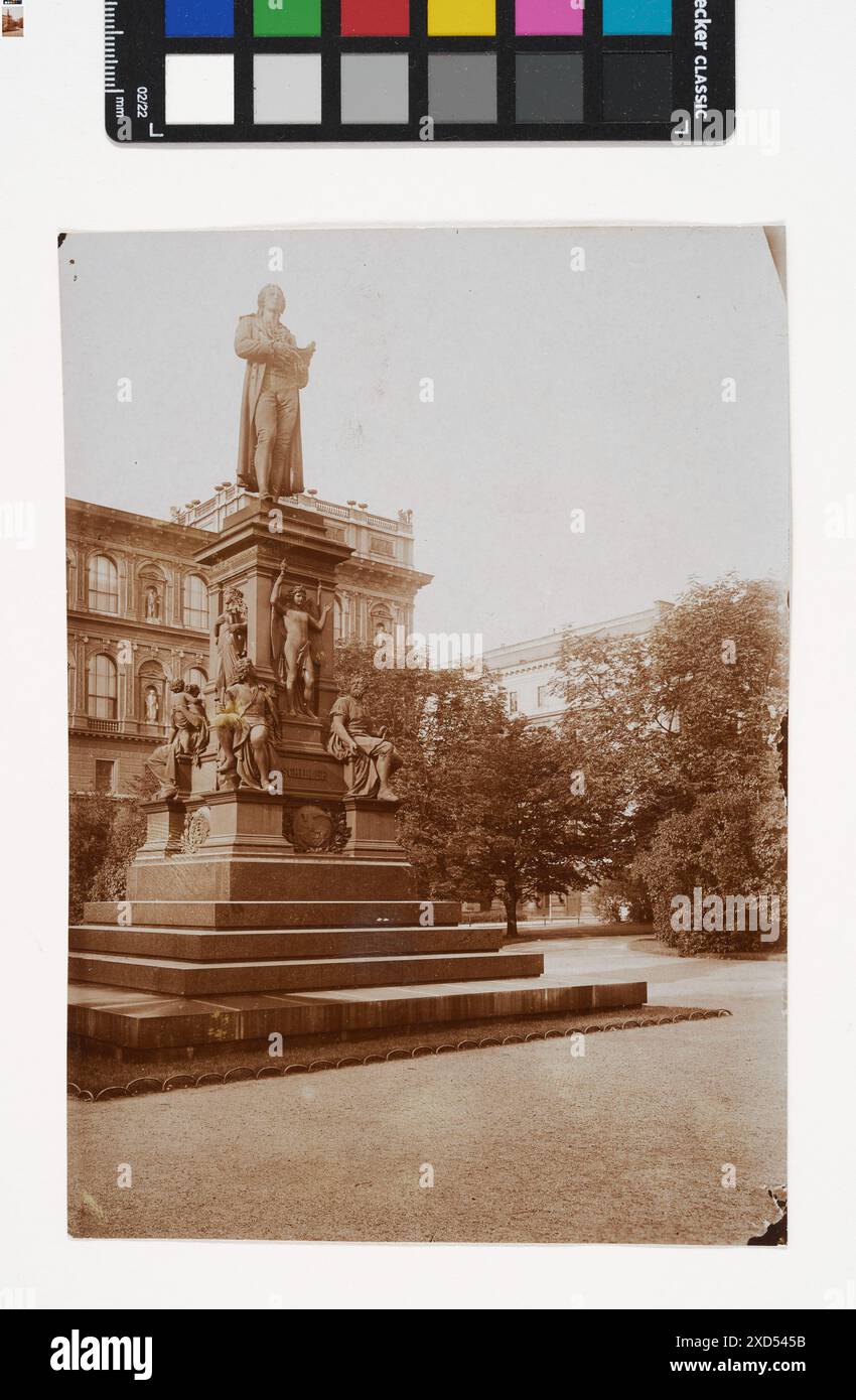 Blick auf den Schillerplatz mit dem Schiller-Denkmal, einer Statue des Dichters Friedrich Schiller, in öffentlichen Gärten in der Nähe eines Universitätsgebäudes nach 1900. Stockfoto