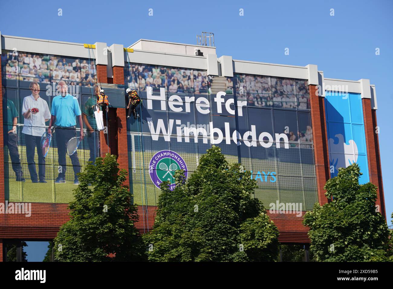 London, Großbritannien. 20. Juni 2024. Ein Gebäude im Stadtzentrum von Wimbledon ist mit riesigen Horten „Here for Wimbledon“ von der Barclay Bank als offizieller Sponsor der Wimbledon-Tennismeisterschaften, die am 1-14. Juli beginnen, bedeckt. Barclays wurde wegen seiner Unterstützung für Projekte mit fossilen Brennstoffen kritisiert Credit: Amer Ghazzal/Alamy Live News Stockfoto