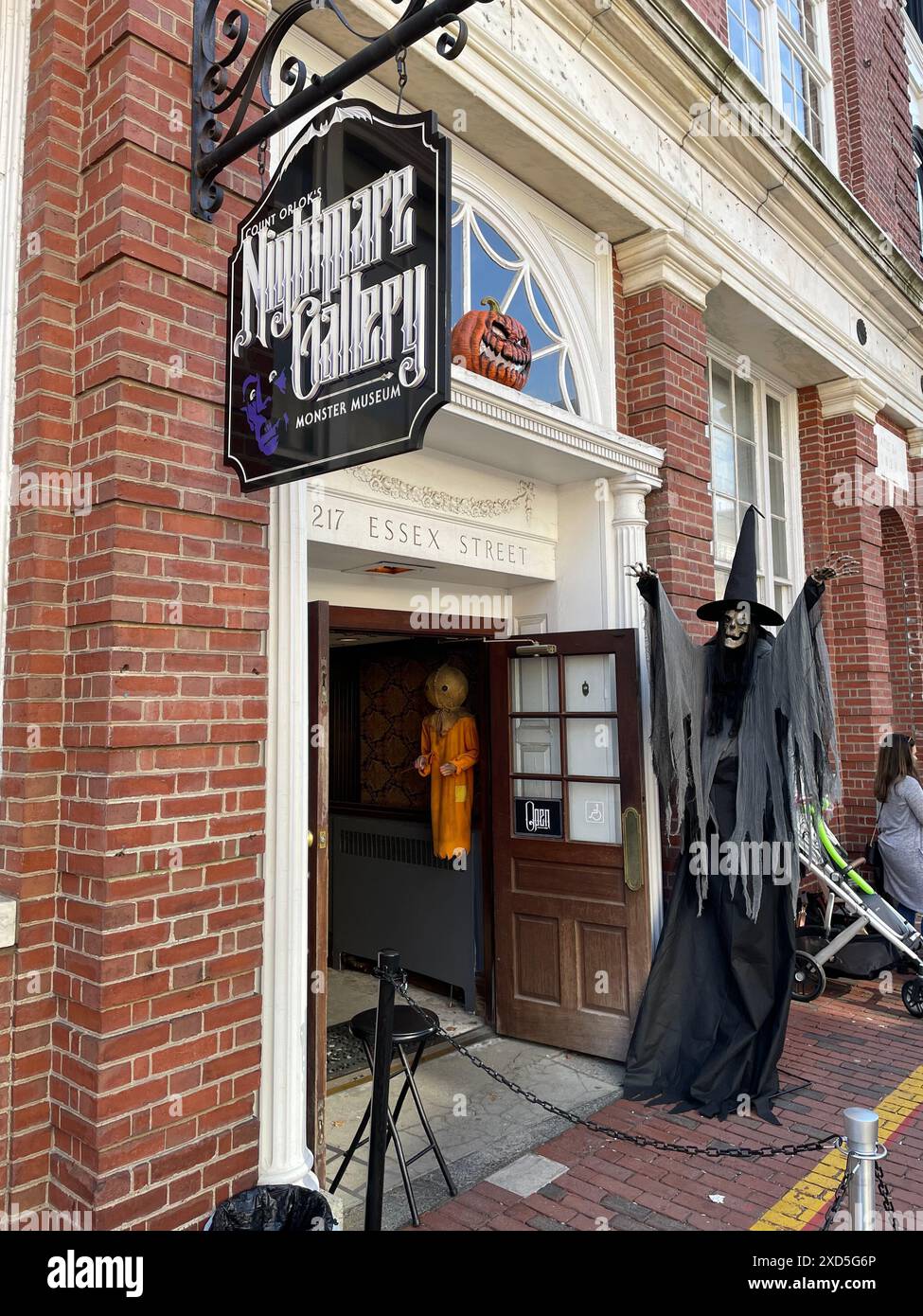 Eine Hexe mit erhobenen Armen steht vor einem Laden, in dem unheimliche und gruselige Gegenstände rund um Halloween in Salem Massachusetts verkauft werden Stockfoto