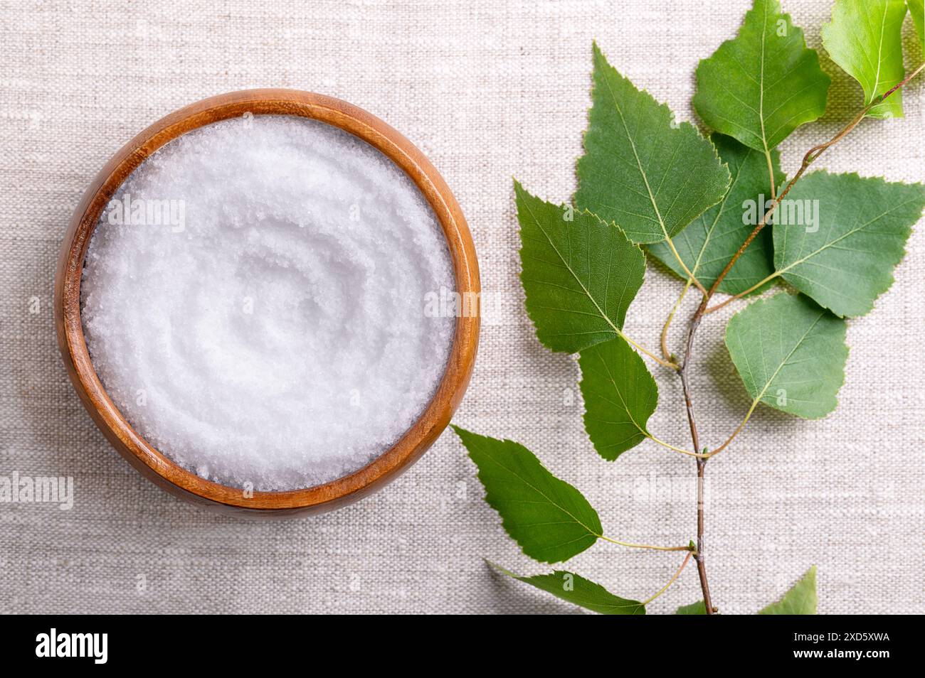 Birkenzucker, Tafelsüßmittel auf Xylit-Basis, in einer Holzschale auf Leinengewebe. Auch Xylit genannt, ein Zuckerersatz natürlichen Ursprungs. Stockfoto