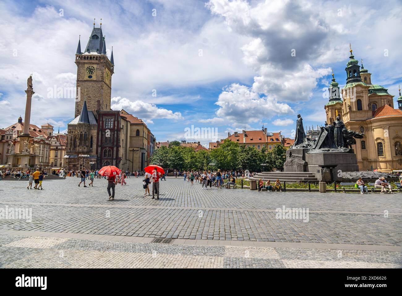 Prags Altstädter Ring voller Touristen, darunter das Alte Rathaus, das Jan Hus-Denkmal und die Nikolaikirche unter einem leuchtend blauen Himmel. Stockfoto