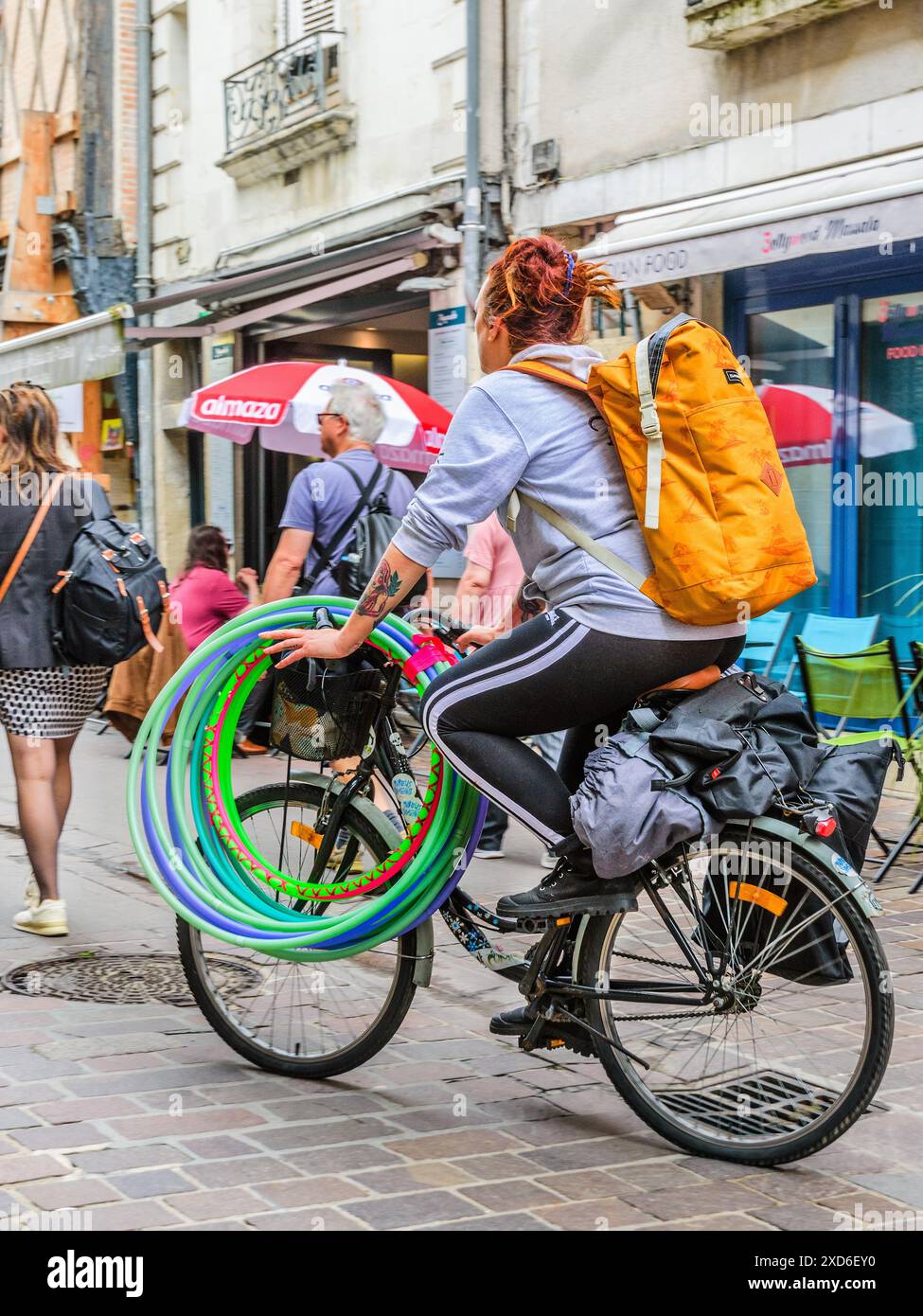 Frau auf dem Fahrrad mit einem Dutzend bunten Hula Hoop - Tours, Indre-et-Loire (37), Frankreich. Stockfoto