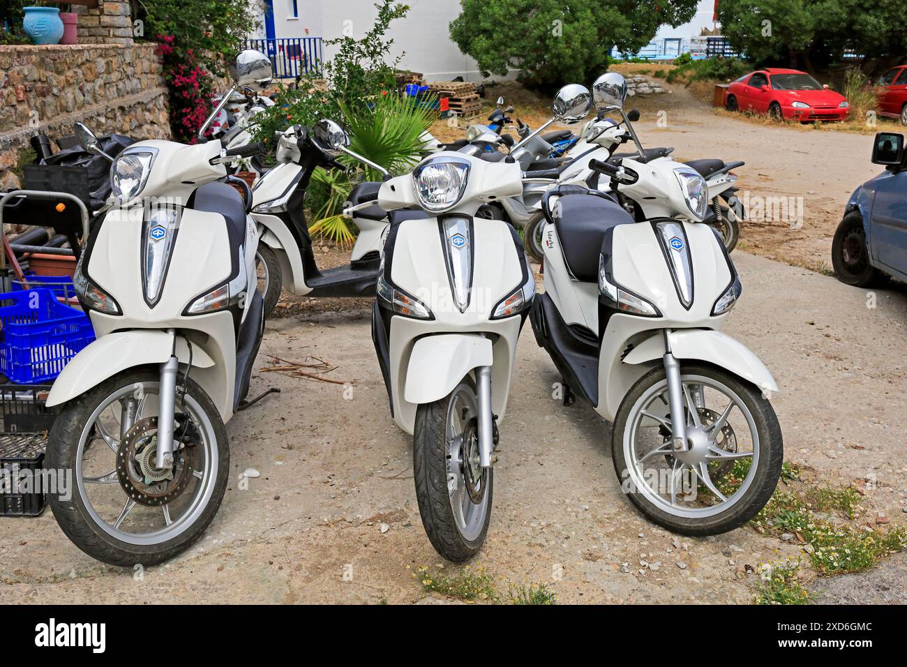 Drei weiße Motorroller parken am Straßenrand und können gemietet werden, Tilos Island, Dodekanese, Griechenland. Vom Mai 2024 Stockfoto
