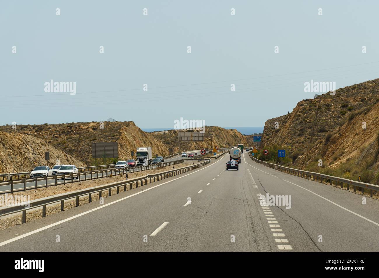 Almeria, Spanien - 25. Mai 2023: Blick auf eine Autobahn, die durch einen Bergpass in Spanien führt. Es gibt mehrere Autos und Lastwagen, die entlang der Roa fahren Stockfoto