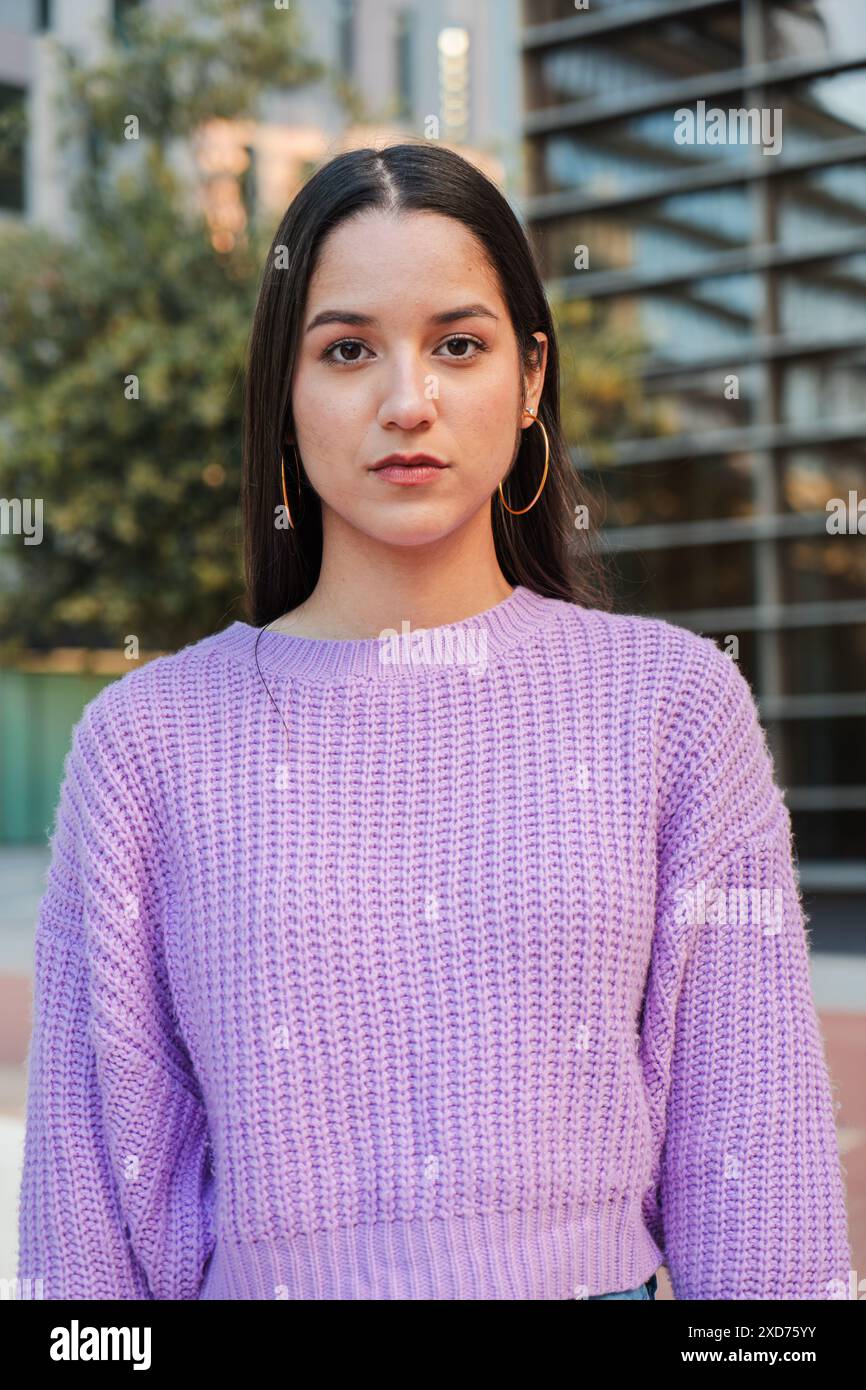 Vertikal Ein Porträt einer entschlossenen jungen Latina-Schülerin, die allein steht, mit einem reflektierenden Ausdruck vorwärts blickt, Vertrauen und Selbstbewusstsein ausstrahlt. Frau, die ernsthaft in die Kamera schaut. Hochwertige Fotos Stockfoto