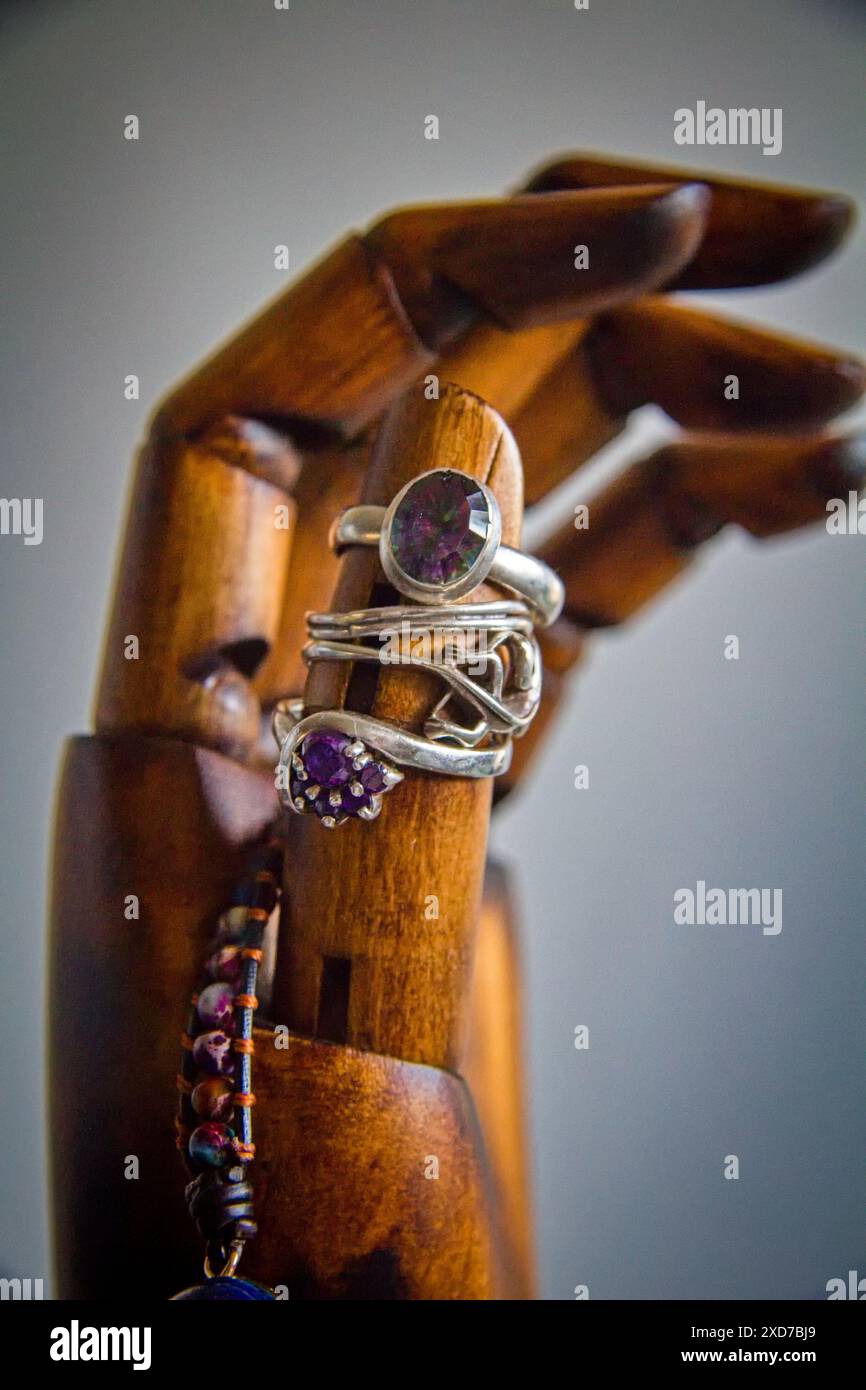 Ringe und andere Schmuckstücke, die auf Holzhand angeordnet sind Stockfoto