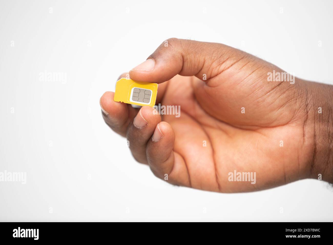 Schwarze Hand hält gelbe SIM-Karte über weißem Hintergrund Stockfoto