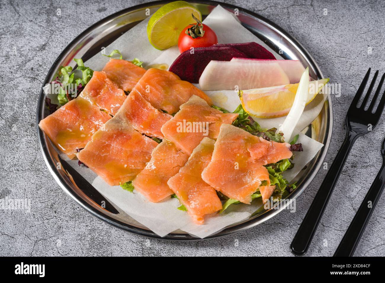 Räucherlachs mit Gemüse darunter auf einem Steintisch Stockfoto