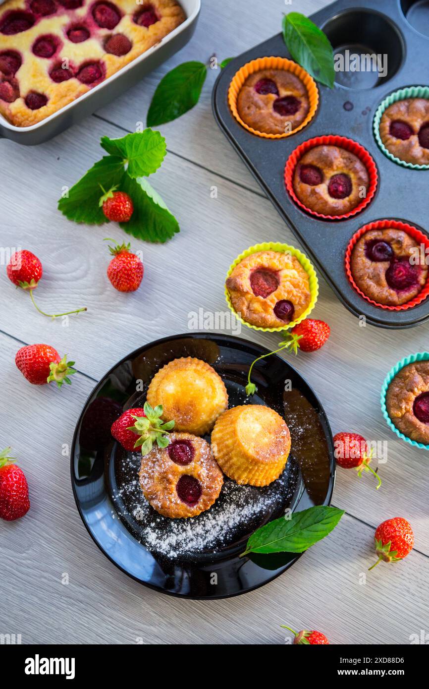 Süße Quark-Muffins mit Erdbeerfüllung, auf einem Teller auf einem Holztisch. Stockfoto