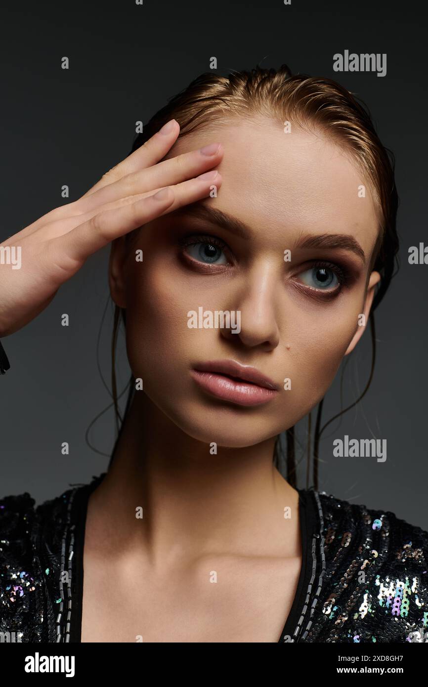 Eine Frau mit fesselnden blauen Augen in einem eleganten schwarzen Oberteil, das ihr nasses Haar zeigt. Stockfoto