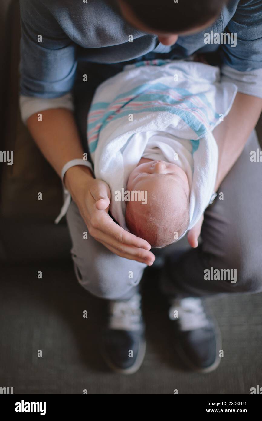 Eine Person, die ein neugeborenes Baby in eine Decke auf dem Schoß legt Stockfoto