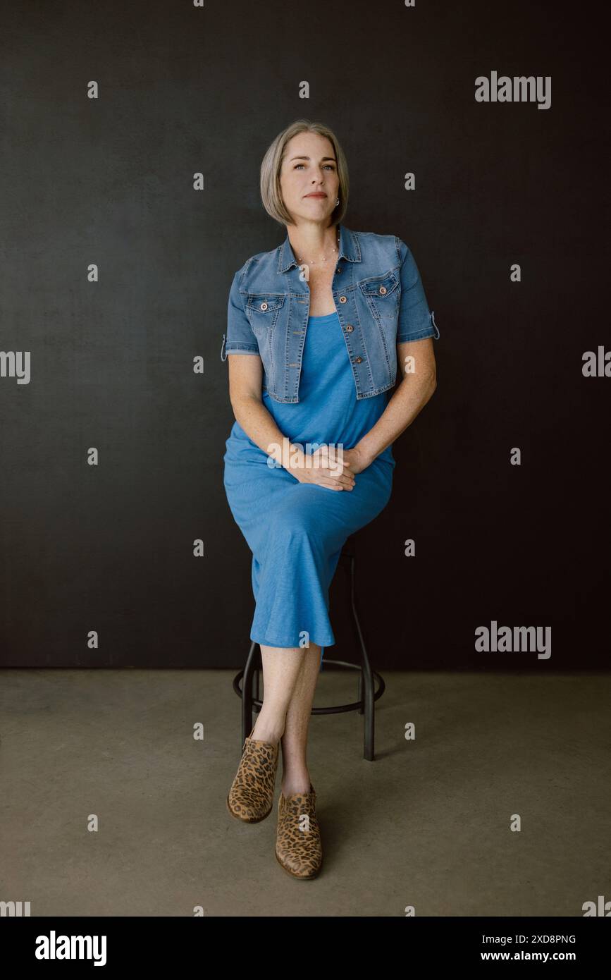 Frau mit grauem Haar in blauem Kleid in einem Studio Stockfoto