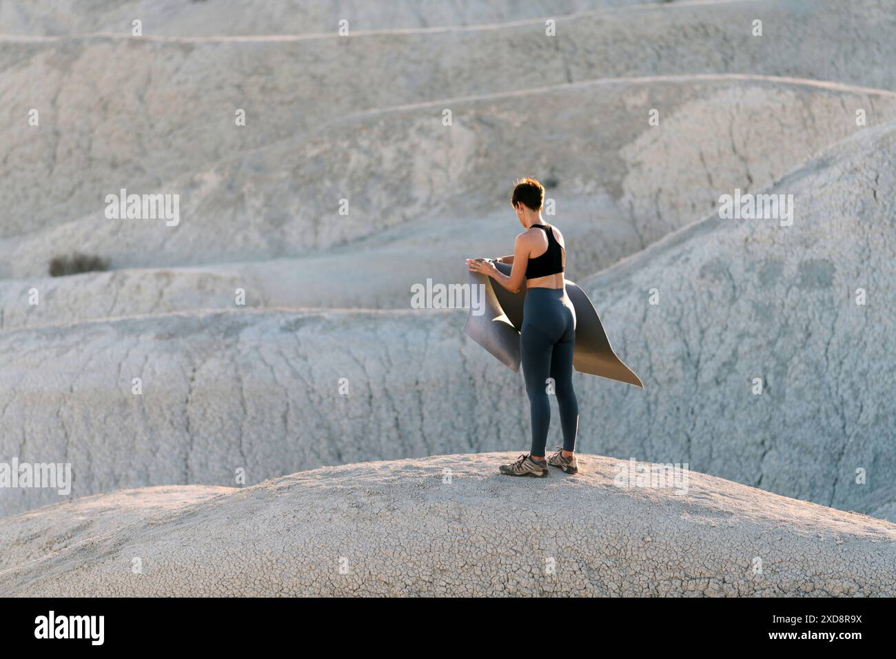 Frau, die Matte für Yoga in der Wüste vorbereitet. Stockfoto