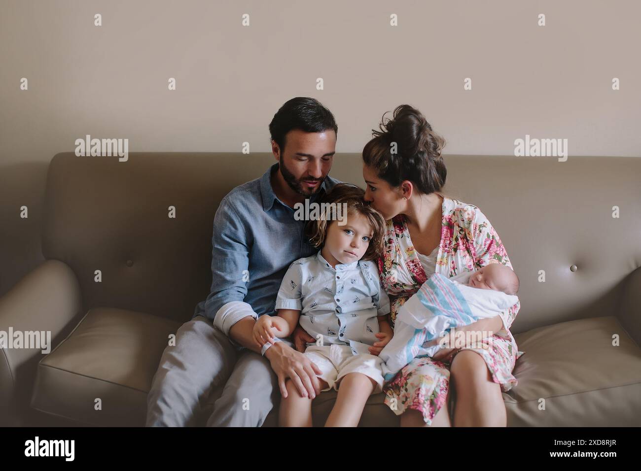 Familie, die mit einem neugeborenen Baby auf einer Couch sitzt, einschließlich eines Mannes, Stockfoto