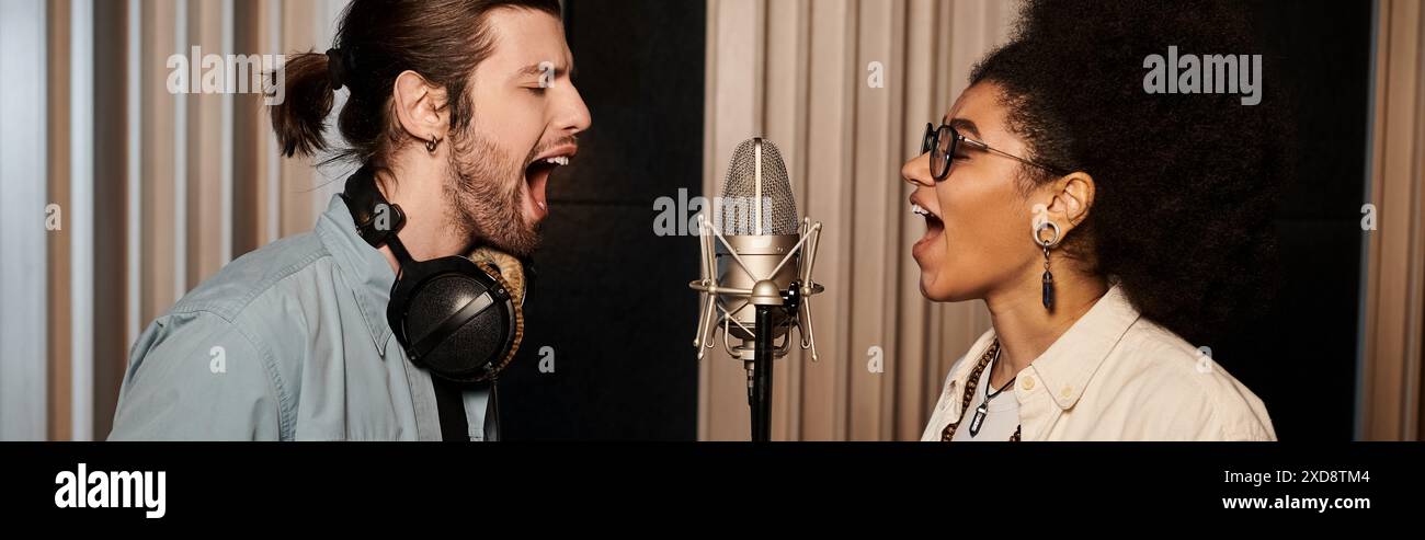 Ein Mann und eine Frau singen mit Leidenschaft in ein Mikrofon während einer Musikbandprobe in einem Aufnahmestudio. Stockfoto