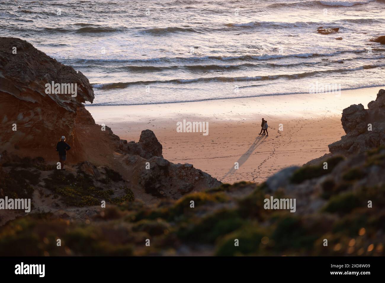 Ein Paar spaziert am Strand bei Sonnenuntergang in Sagres, Algarve, Portugal Stockfoto