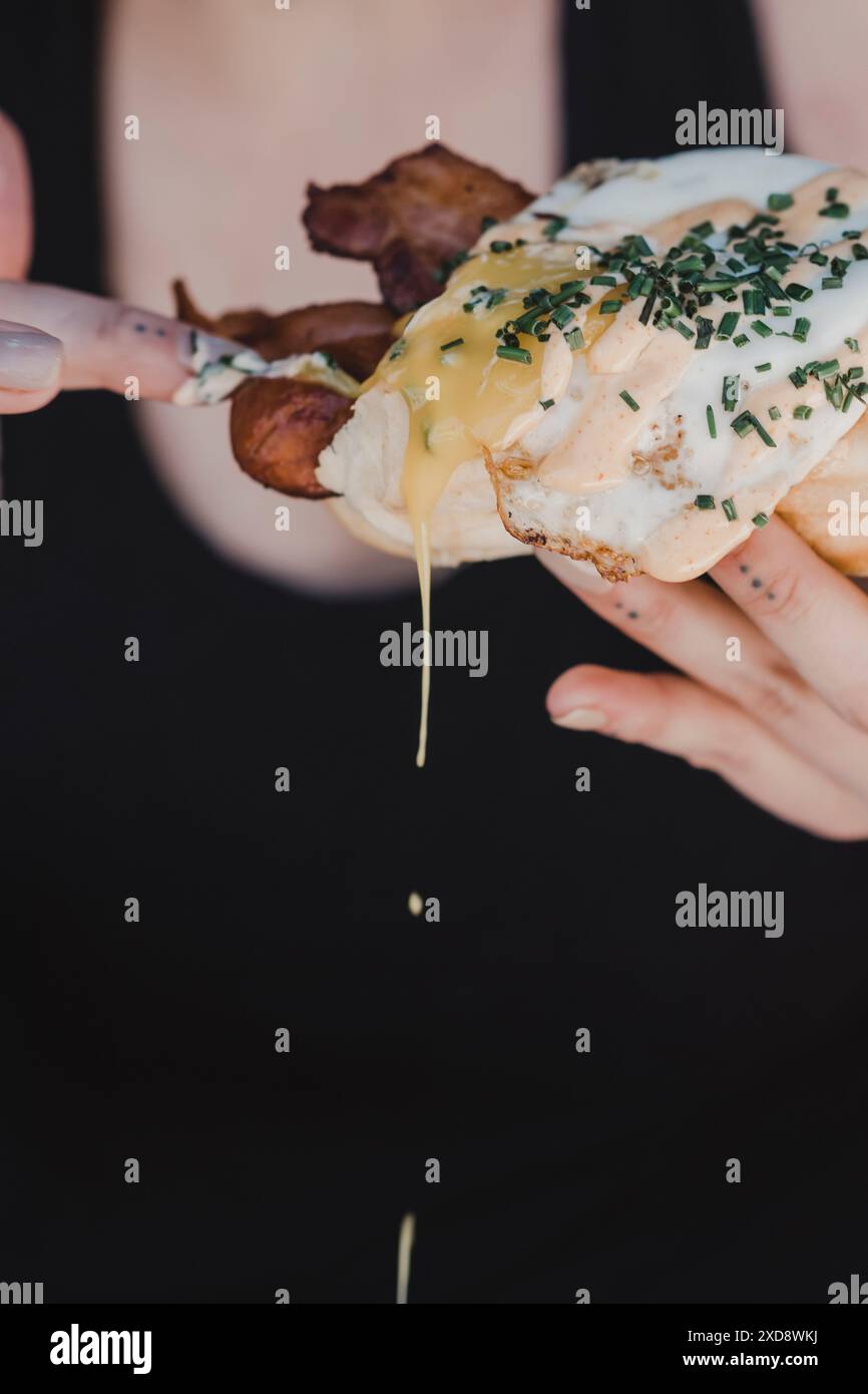 Person mit einem Speck und Ei-Sandwich mit tropfender Sauce. Stockfoto