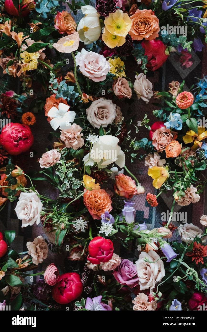 Blick von oben auf ein lebhaftes Blumenarrangement auf einem gemusterten Teppich. Stockfoto