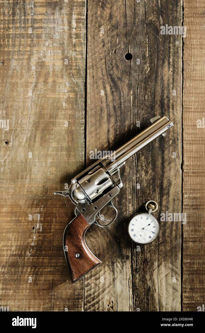 Wilder Westen, bis Mittag. Cowboy 6 Pistolen und silberne Taschenuhr liegen auf einem alten Holztisch. Cowboy, Western, Thema. Stockfoto