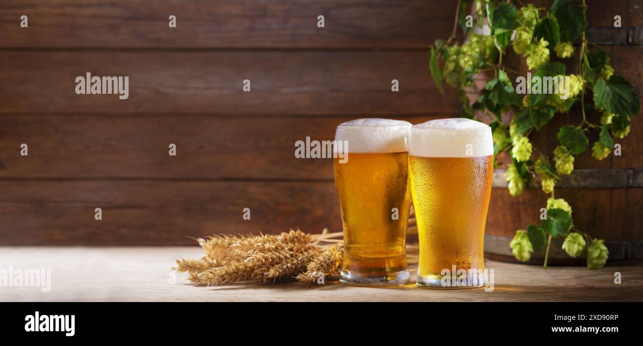 Gläser Bier, Weizenohren und Hopfen auf einem hölzernen Hintergrund Stockfoto