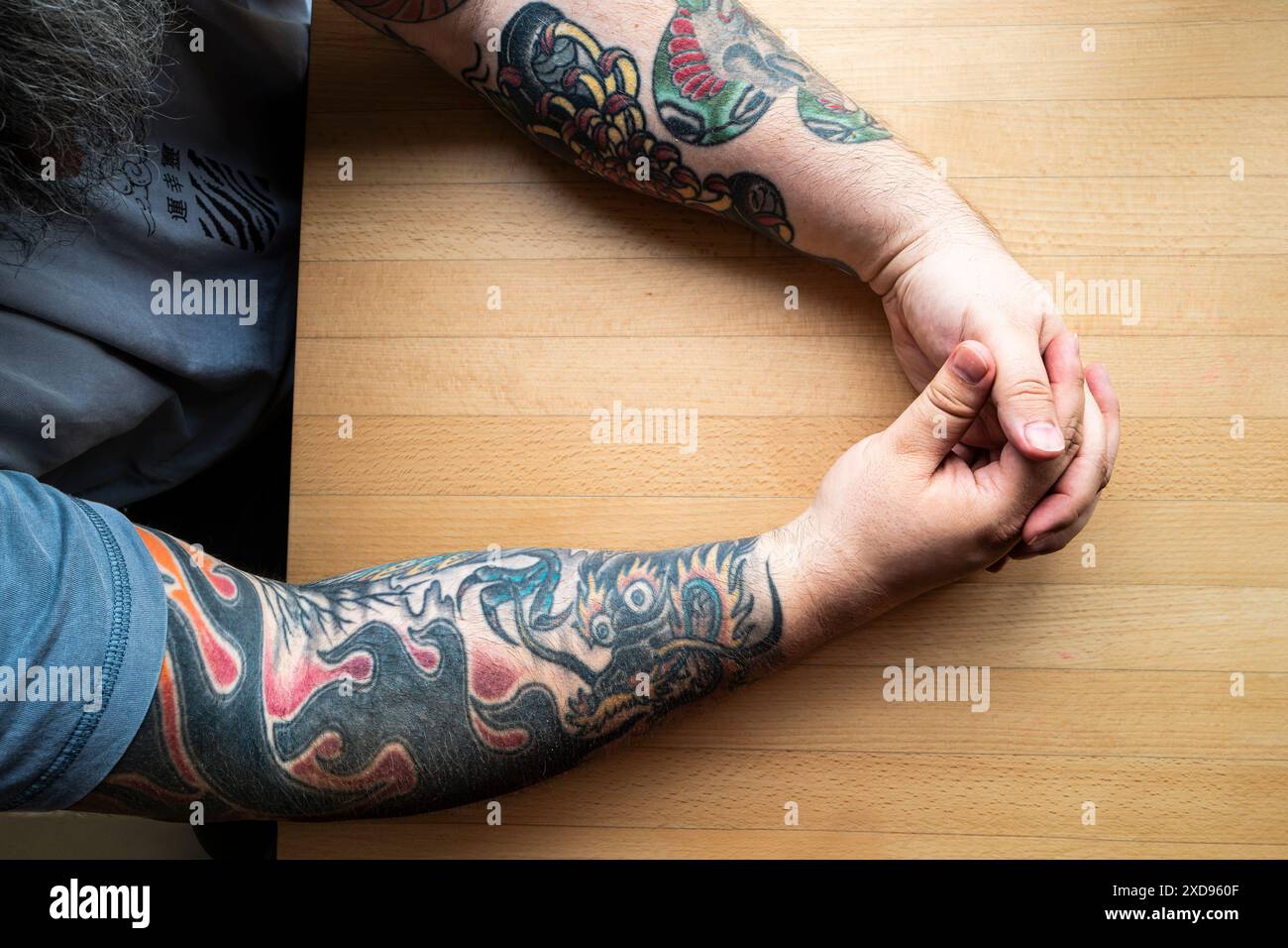 Tätowierte Arme auf einem Tisch in Cornwall in Großbritannien. Stockfoto