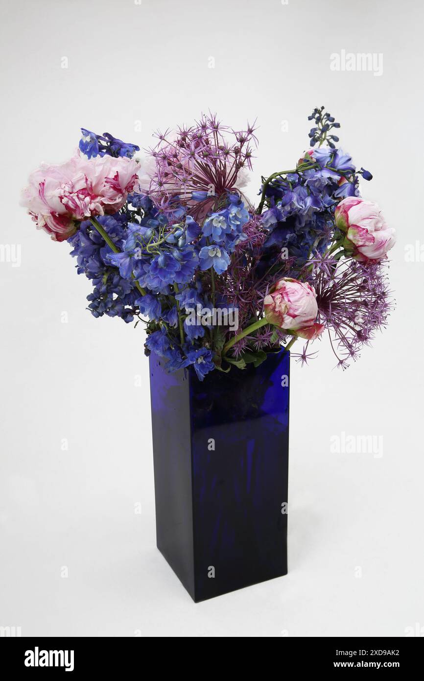 Blumenstrauß mit Pfingstrosen in einer rechteckigen Vase aus blauem Glas Stockfoto