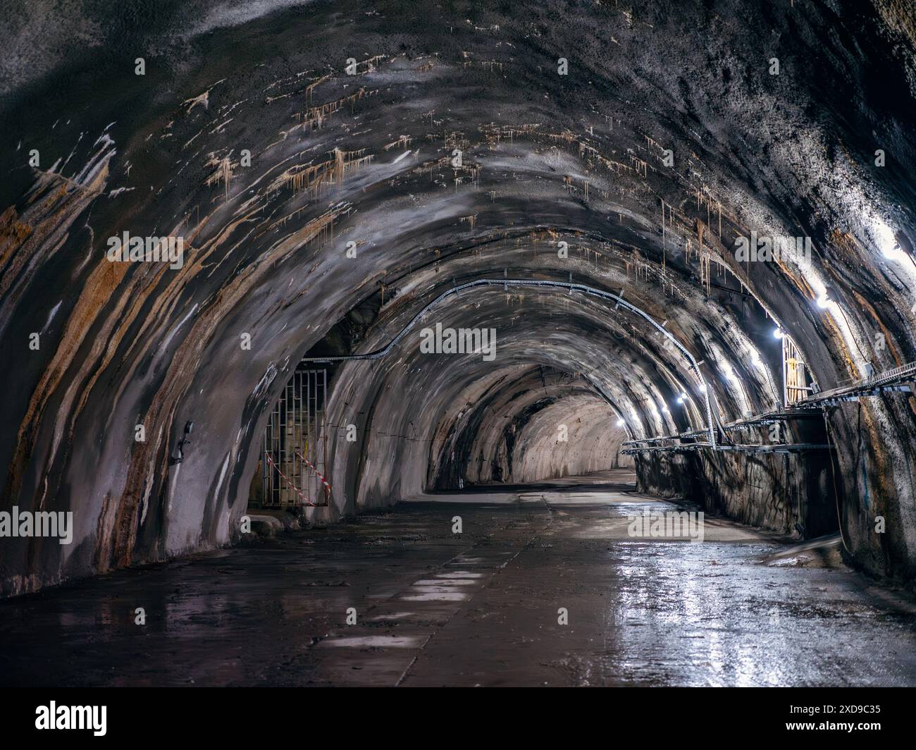 Alter Industrietunnel mit Betonwänden, dunkler künstlicher Beleuchtung und tropfendem Wasser. Stockfoto