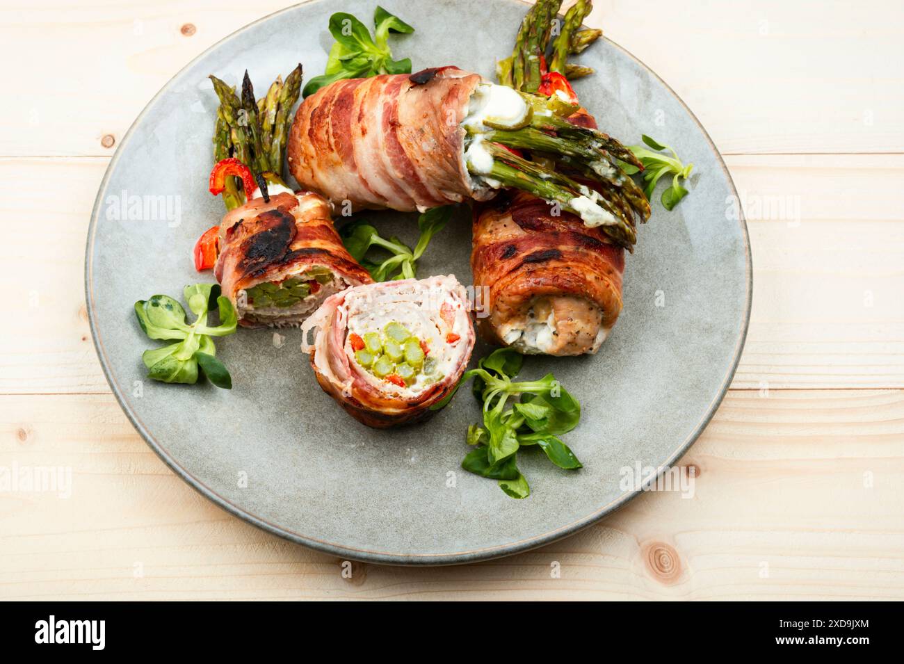 Gebratene Fleischbrötchen gefüllt mit grünem jungen Spargel auf Holztisch. Stockfoto