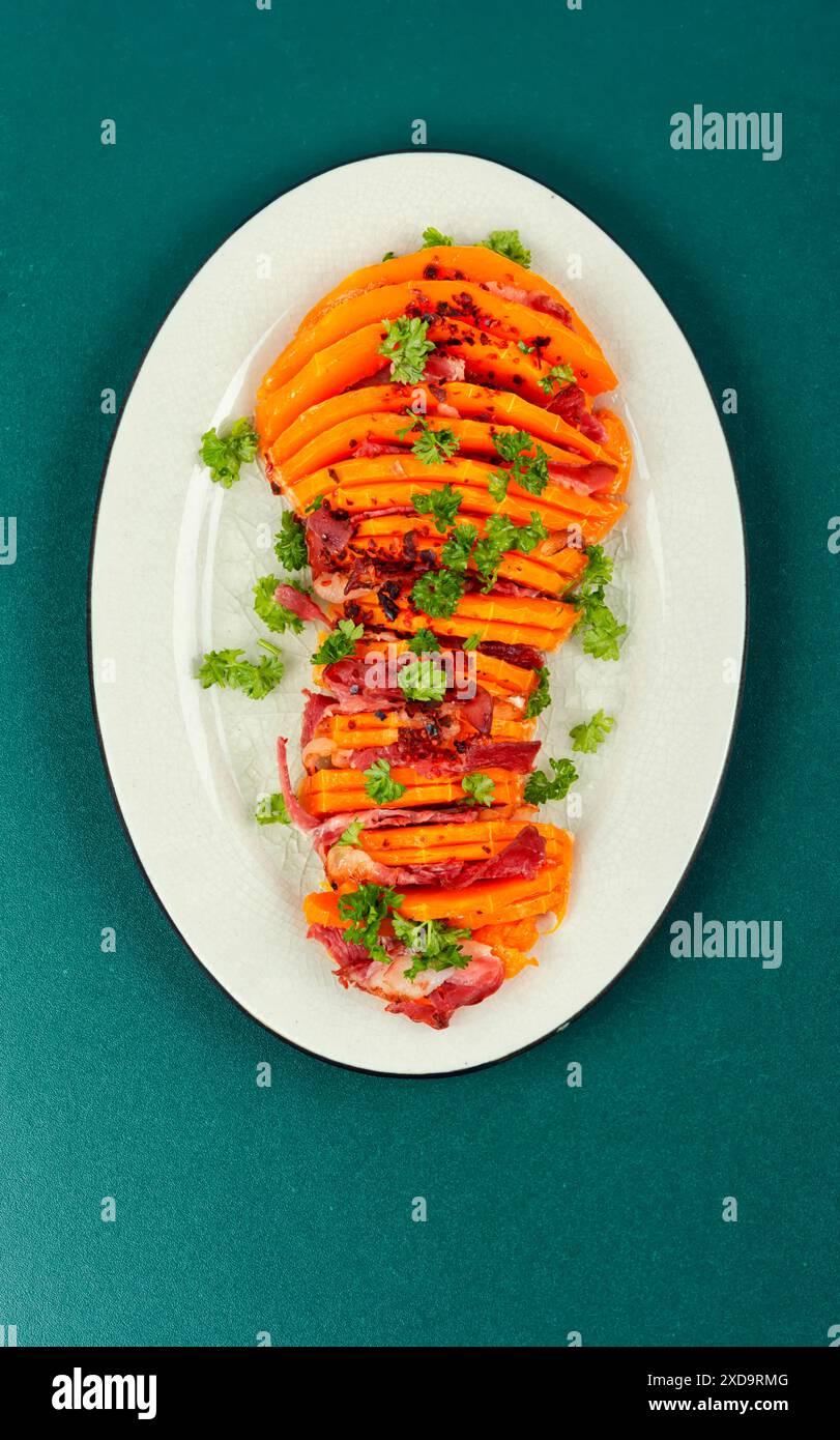 Köstlicher gebackener Butternusskürbis. Gebackener Kürbis aus Butternusskürbis, gefüllt mit Speck. Stockfoto