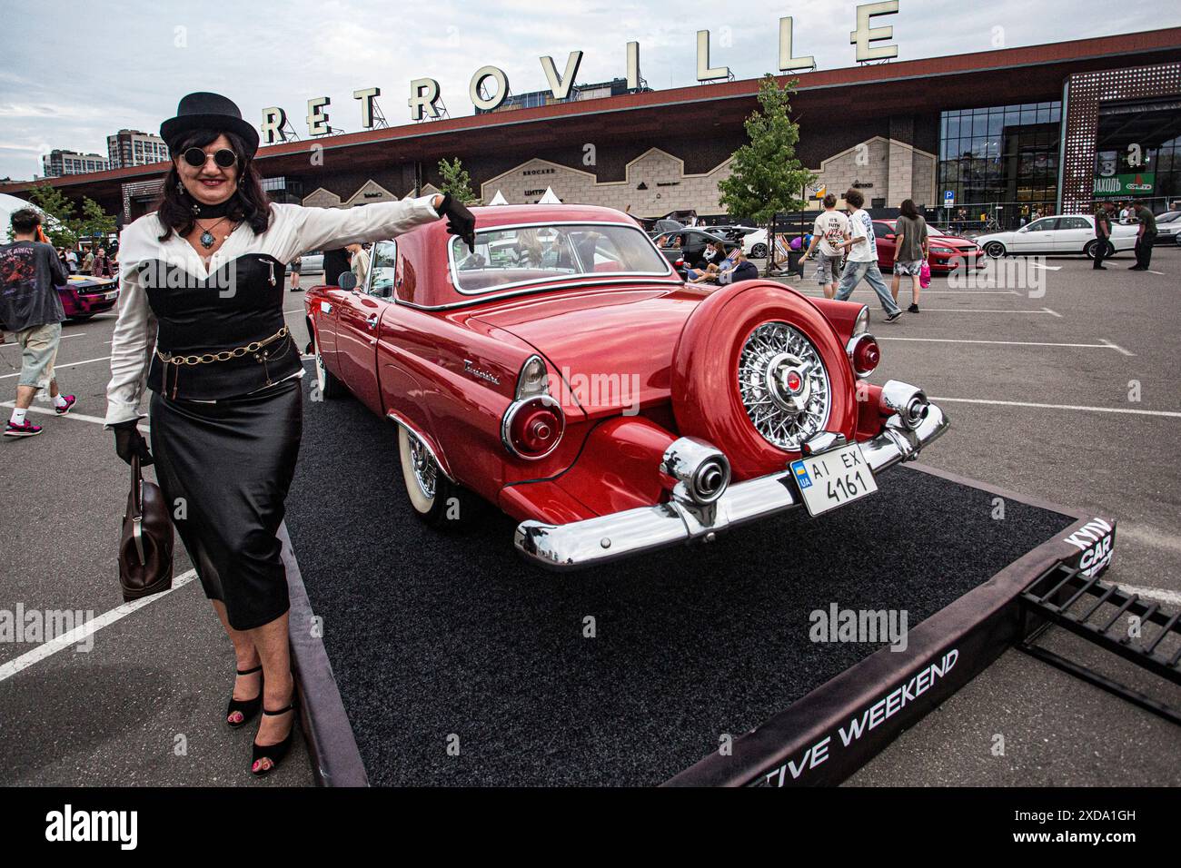 Eine verkleidete Dame zeigt auf dem 1953er Ford Thunderbird auf dem Kyiv Car fest auf dem Parkplatz Retroville im westlichen Teil von Kiew im Juni 2024 Stockfoto