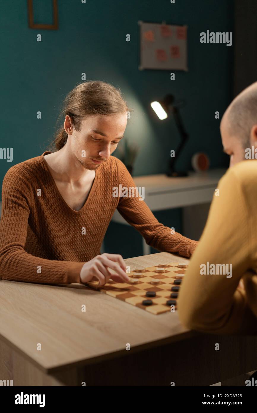 Freunde, die zu Hause Ein Spiel der Checkers genießen. Freundliches Checkers Match, Freizeit Im Komfortablen Wohnzimmer. Stockfoto