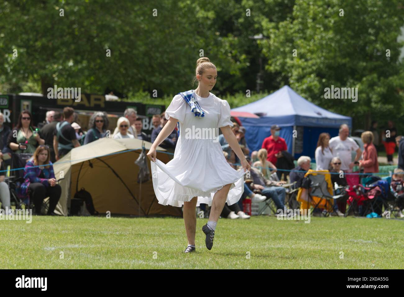 Eine Frau tanzt einen traditionellen schottischen Hochlandtanz in einem weißen Kleid als Teil des Pipes in the Park Events in Colchester, Essex im Jahr 2024. Stockfoto