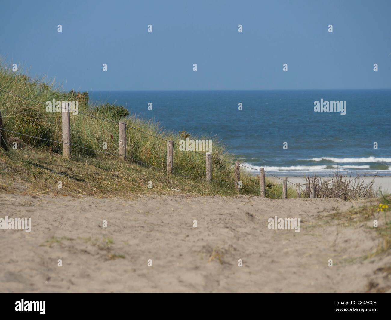 Sandstrand mit Dünen und einfachem Zaun, ruhiges Meer im Hintergrund, Juist, Ostfriesland, Deutschland Stockfoto