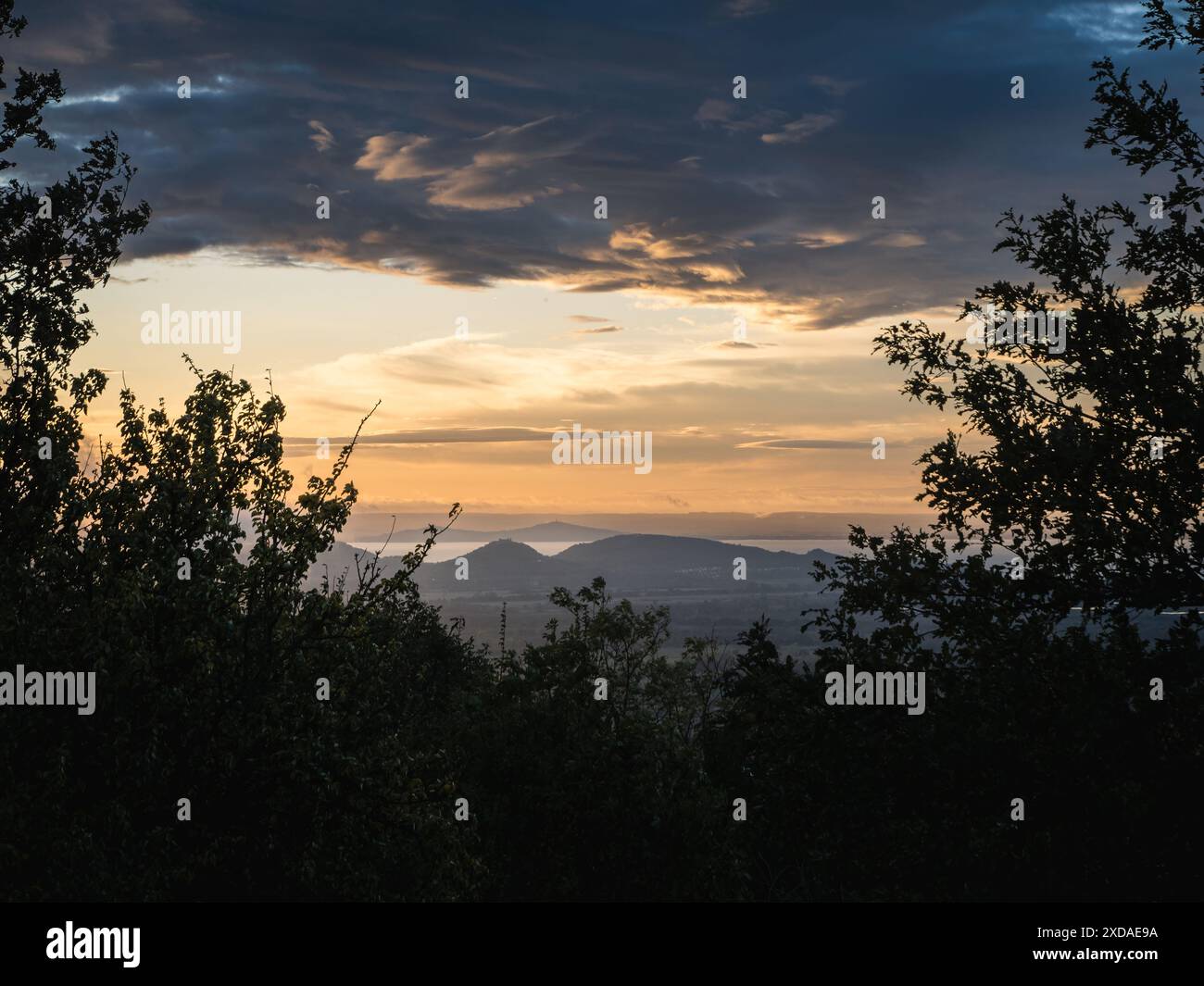 Sonnenuntergang mit dramatischem bewölktem Himmel über dem Balaton mit der Burg von Szigliget im Hintergrund, Herbst, regnerisches Wetter, nationaler blauer Pfad Stockfoto