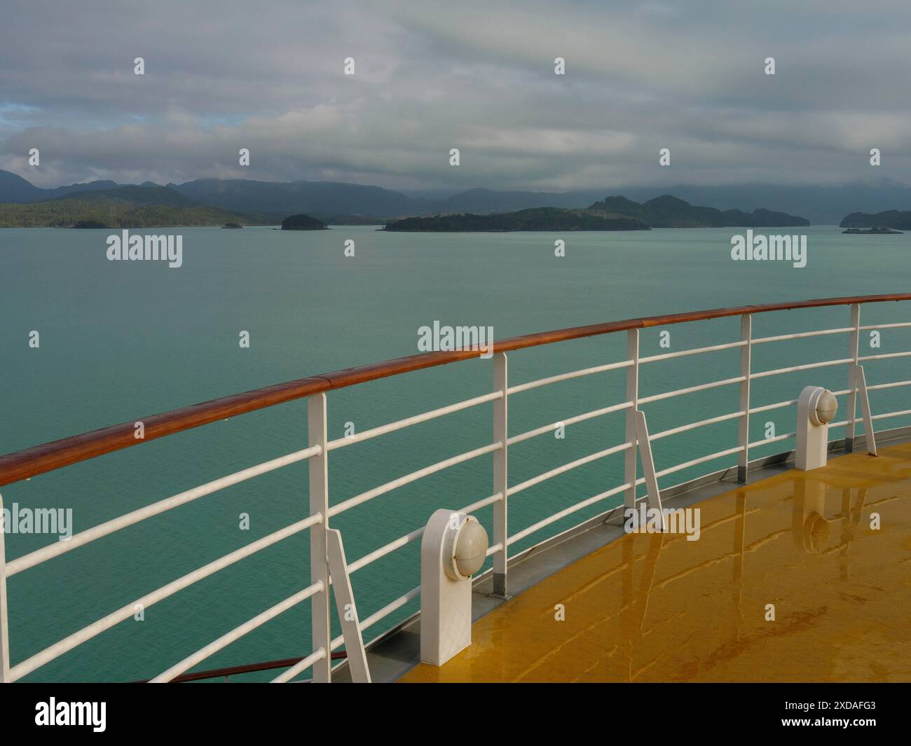 Blick vom Deck eines Schiffes mit ruhigem Wasser und fernen Inseln unter einem trüben Himmel, Eidfjord, norwegen Stockfoto