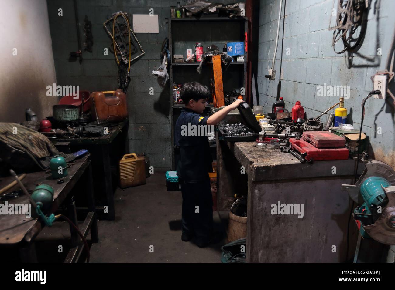 Maracaibo, Venezuela.5-14-2024. Alejandro Matias kommt nach der Schule in die Werkstatt seines Vaters, um seinem Vater als Mechaniker zu helfen. Foto Von. Jose I. Bula Stockfoto