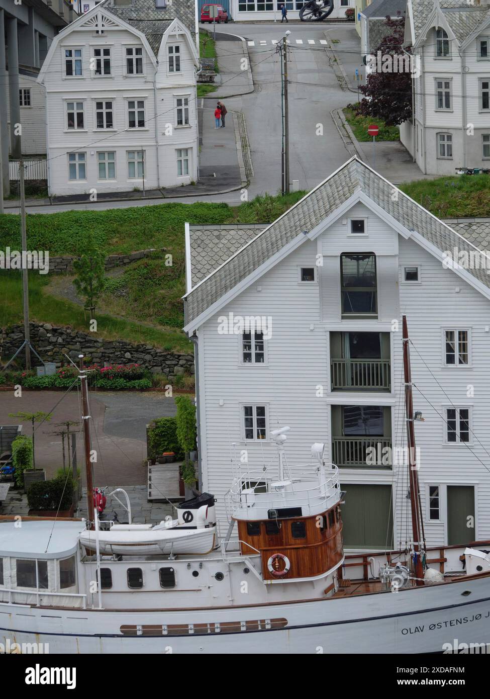 Historisches Schiff neben weißen Gebäuden in einer kleinen Stadt unter bewölktem Himmel, haugesund, norwegen Stockfoto