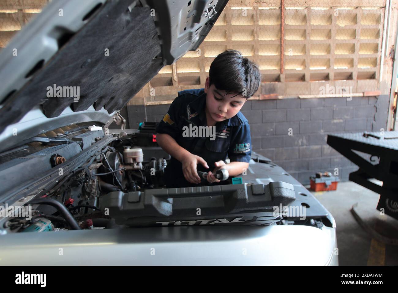 Maracaibo, Venezuela.5-14-2024. Alejandro Matias kommt nach der Schule in die Werkstatt seines Vaters, um seinem Vater als Mechaniker zu helfen. Foto Von. Jose I. Bula Stockfoto