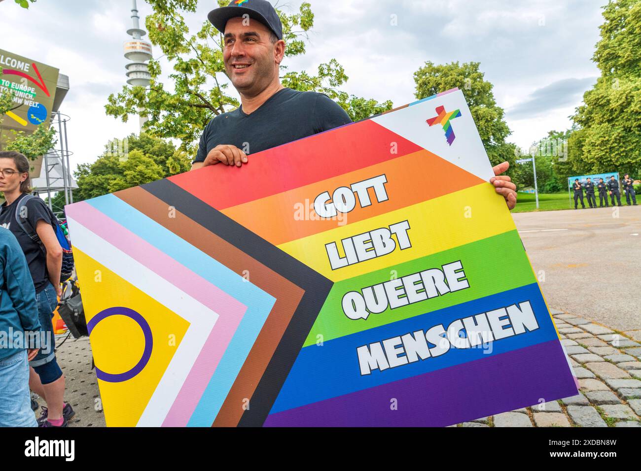 Gott liebt queere Menschen, queerer Protest gegen die UNUM24 Glaubenskonferenz, München, 21. Juni 2024 Deutschland, München, 21. Juni 2024, Gott liebt queere Menschen, Schild in Regenbogenfarben, Queerer Protest gegen die UNUM24 Glaubenskonferenz, die in der Olympiahalle stattfindet, Teilnehmer mit T-Shirt-Aufschrift: queer, geliebt, gesegnet, Teilnehmer demonstrieren am Brundageplatz gegen die christlich-konservative ein sein Konferenz, Motto der Demo NoUNUM24, die UNUM24 ist eine überkonfessionelle Glaubenskonferenz in der Olympiahalle vom 20.-23. Juni 2024, Motto Einssein, lateinisch UNUM, Stockfoto