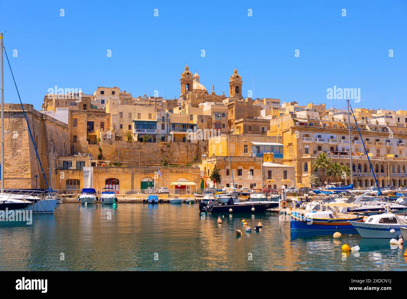 Die Altstadt von Senglea auf Malta. Das Wasser ist mit Booten verschiedener Größe gefüllt, darunter einige, die an einem Pier angedockt sind. Die Szene hat einen friedlichen und seh Stockfoto