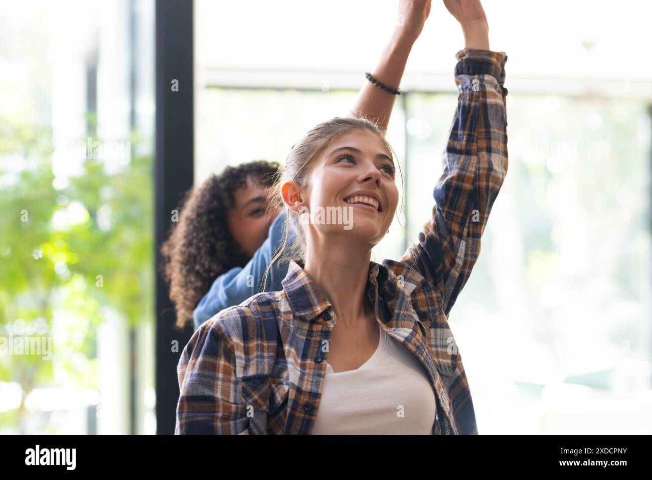 Lächelnd und Arm hebend, zwei Frauen genießen die gemeinsame Zeit zu Hause Stockfoto