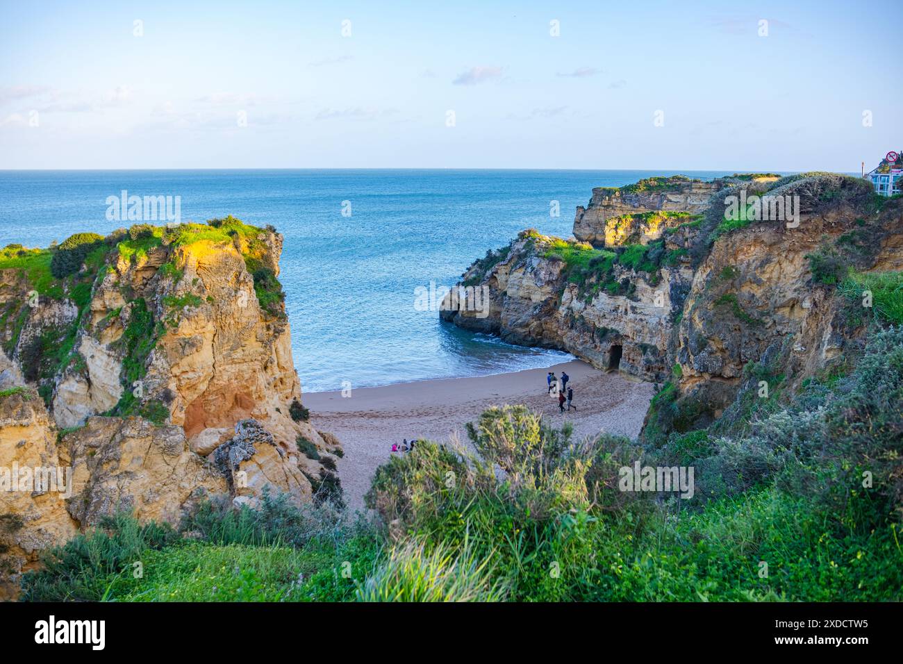 Wunderschöner Meeresstrand in Lagos 'Praia da Batata' mit grasbewachsenen hohen Klippen und wunderschönen Grotten. Panorama auf Strand und Meer. Stockfoto