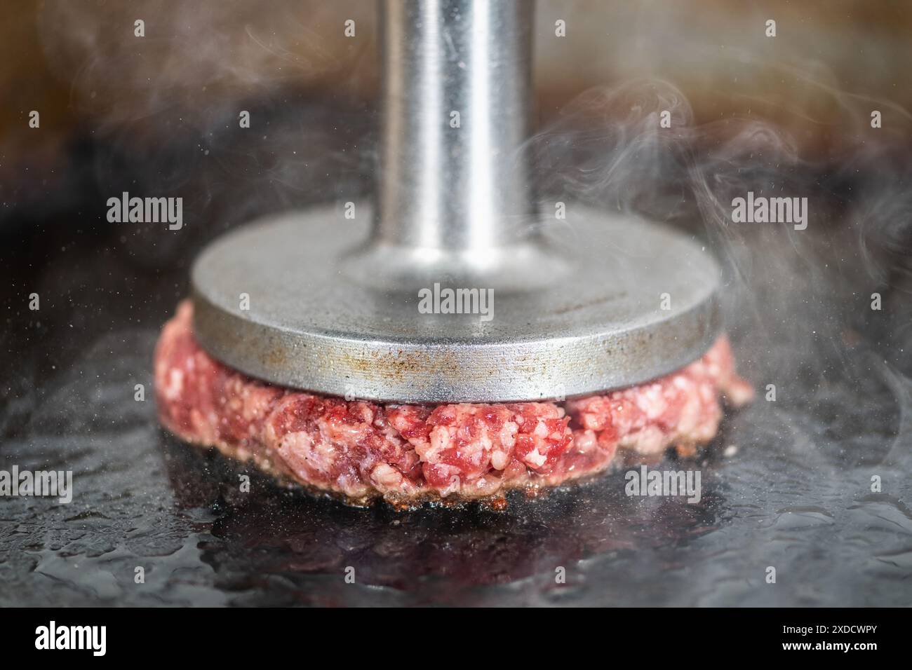 Zubereitung von Burger Patties auf dem Grill mit Burger Smasher. Stockfoto
