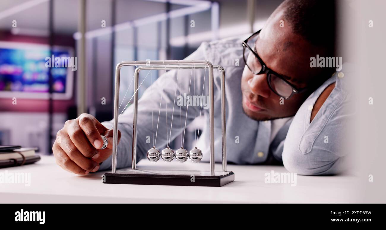 Der überarbeitete afroamerikanische Büroleiter an seinem Schreibtisch: Ein gestresster Mann, der an Deadlines arbeitet, Multitasking auf dem Laptop. Beschreibt Büro, Effizienz, Stockfoto