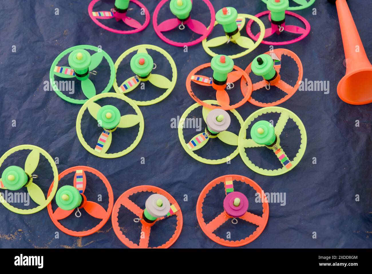 Lebendige, drehbare Oberteile in Bewegung sorgen für eine verspielte Szene. Helle Farbtöne verwischen vor dunklem Hintergrund und halten die Freude an klassischen Kinderspielen fest. Stockfoto