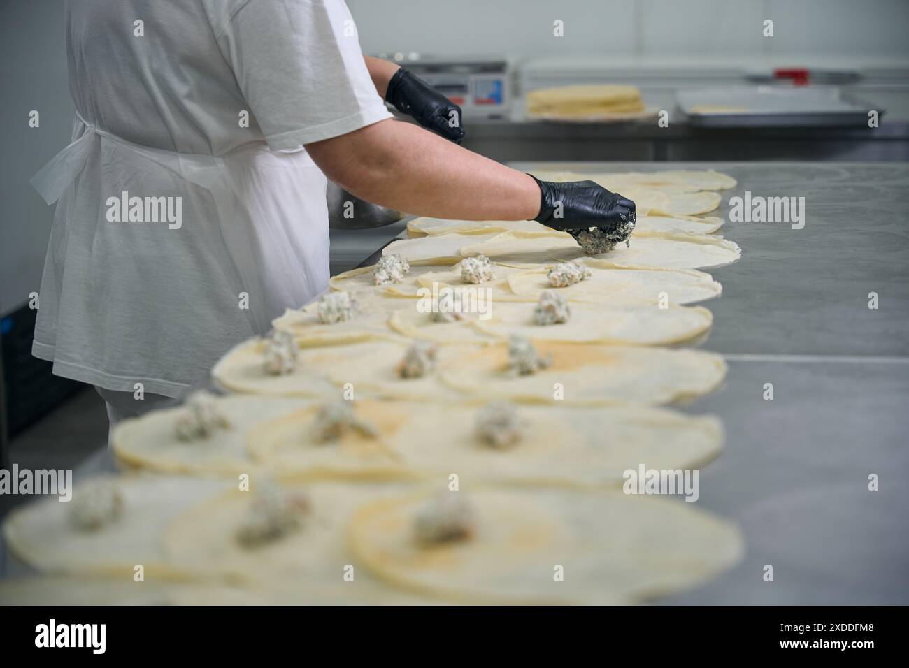 Küchenangestellter legt Fischfüllung auf runde Pfannkuchen Stockfoto