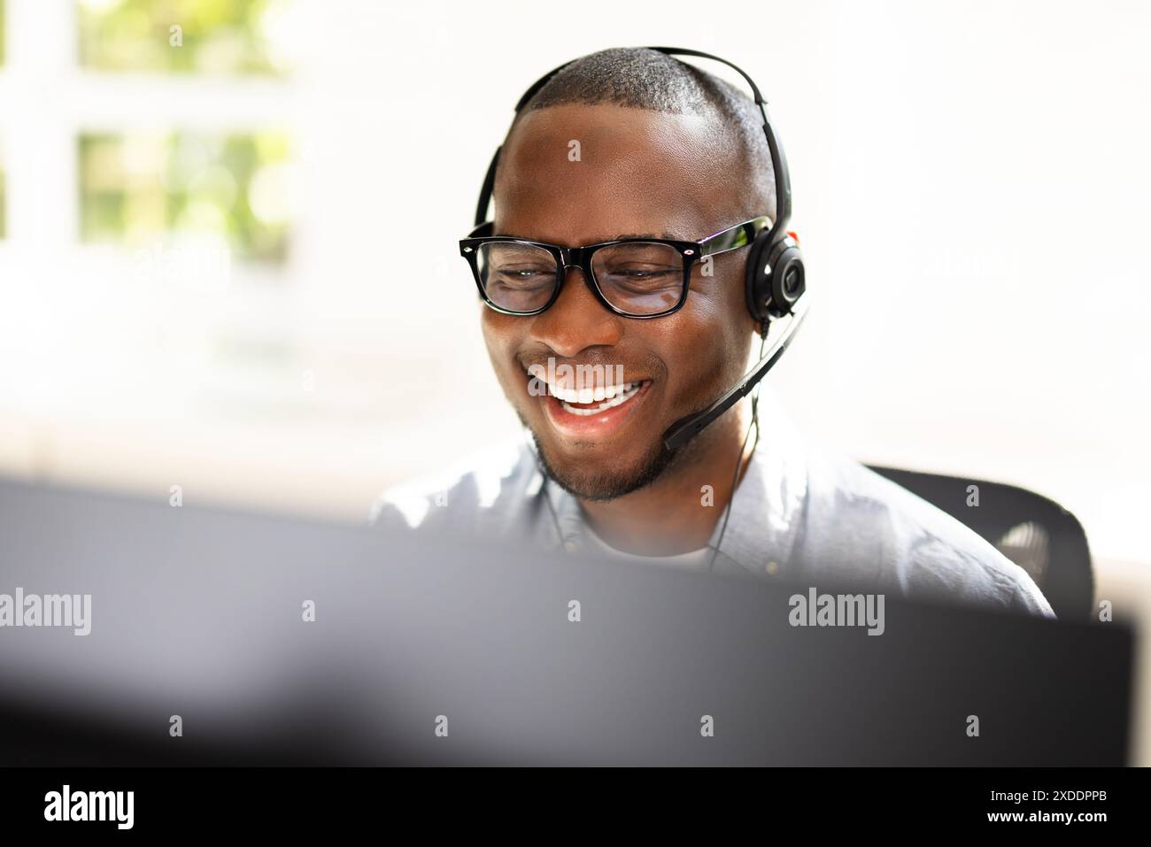 : Energiegeladener Call-Center-Agent, der die Kundenzufriedenheit am Telefon in einer lebhaften Büroumgebung für das technische Support-Team sicherstellt. Stockfoto
