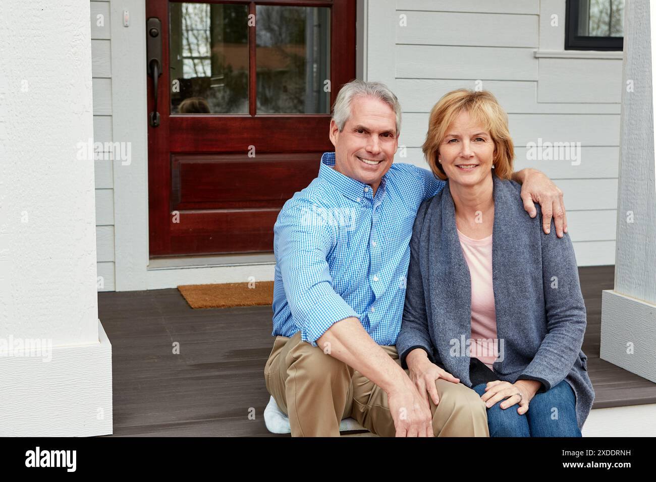 Immobilien, Porträt und Seniorenpaar umarmen sich auf der Veranda mit Umzug, Erfolg oder Altersvorsorge. Hypotheken, Eigentum oder stolze alte Menschen Stockfoto